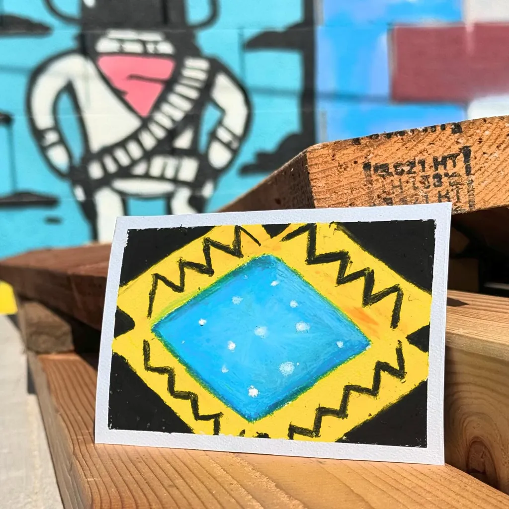 A small, square artwork features a central blue diamond surrounded by yellow zigzags, all contained within a thick black border.
