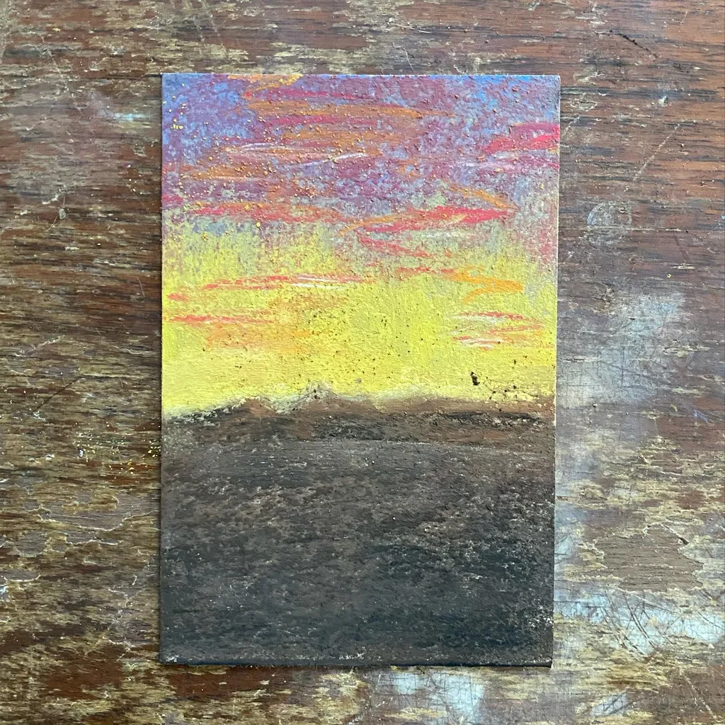 A layered abstract landscape featuring a bright yellow and orange sunset sky above a dark gray, textured foreground, with streaks of red and purple visible near the horizon.