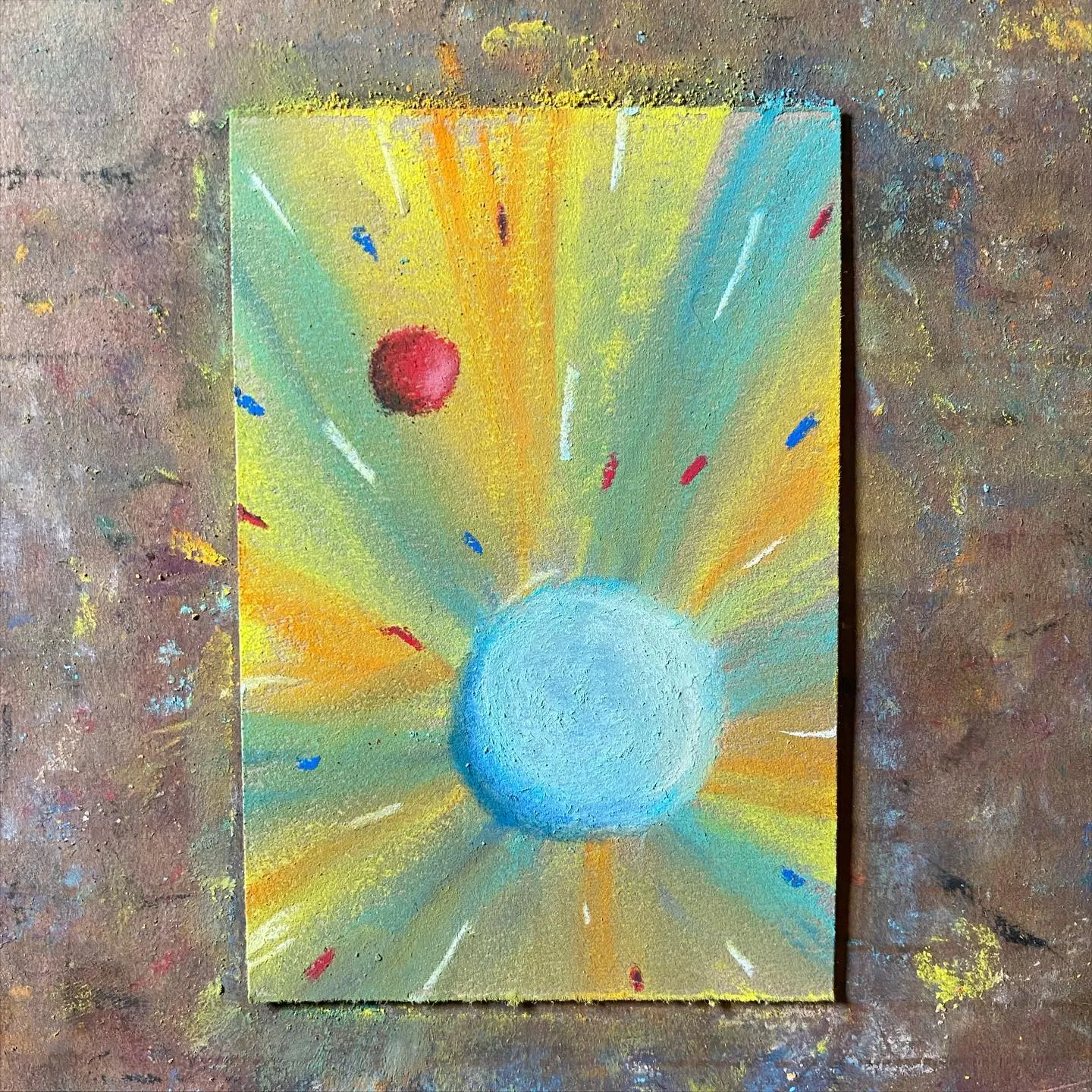 A sunburst painting shows a bright blue circle surrounded by radiating yellow and orange rays, dotted with small red and blue dashes, set against a textured brown background.
