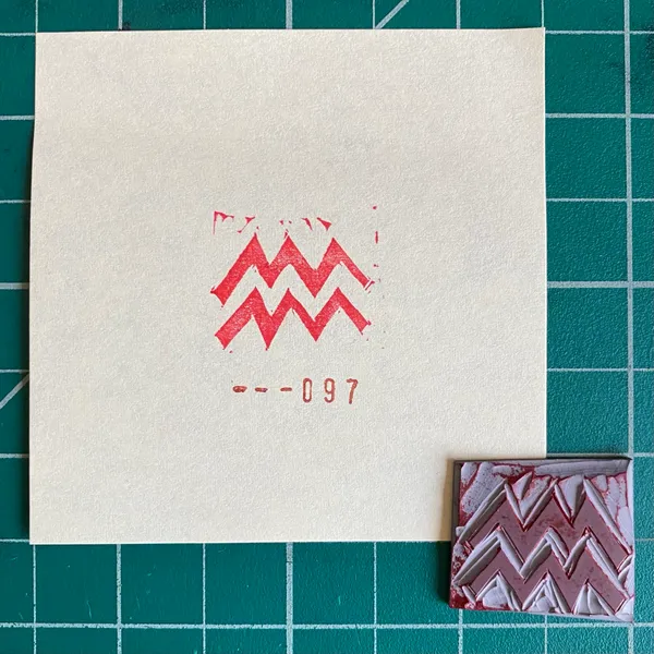 A cream card on a teal grid displays a red zigzag motif and the number --097, positioned next to a small rectangular sample featuring layered red and white zigzags.