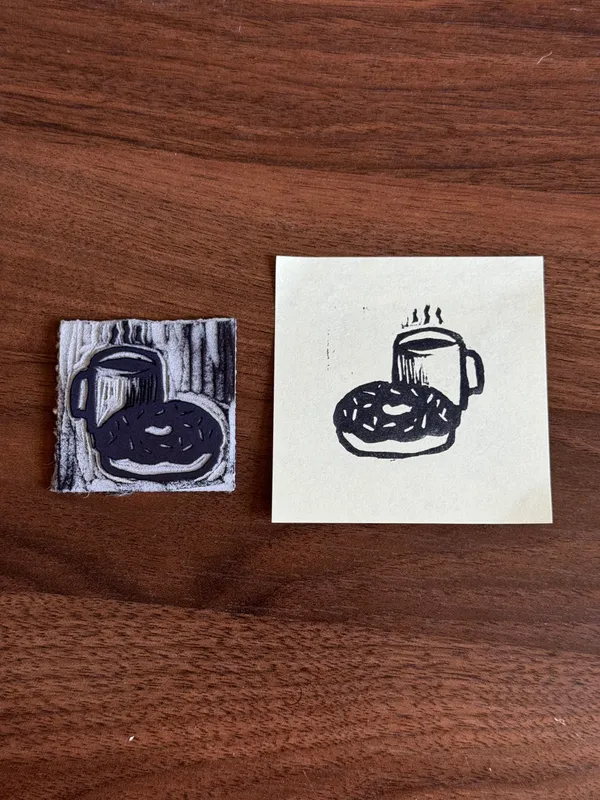 On a dark brown wooden surface, three black ink drawings of coffee cups and round pastries are displayed on two pieces of paper: one set on distressed paper and one set on plain paper.
