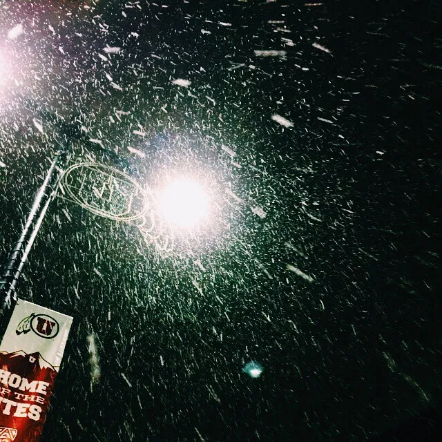 The composition features a dark background with scattered bright specks and streaks, centered by a brilliant white light burst, and includes a red and white object and a pole in the lower left corner.