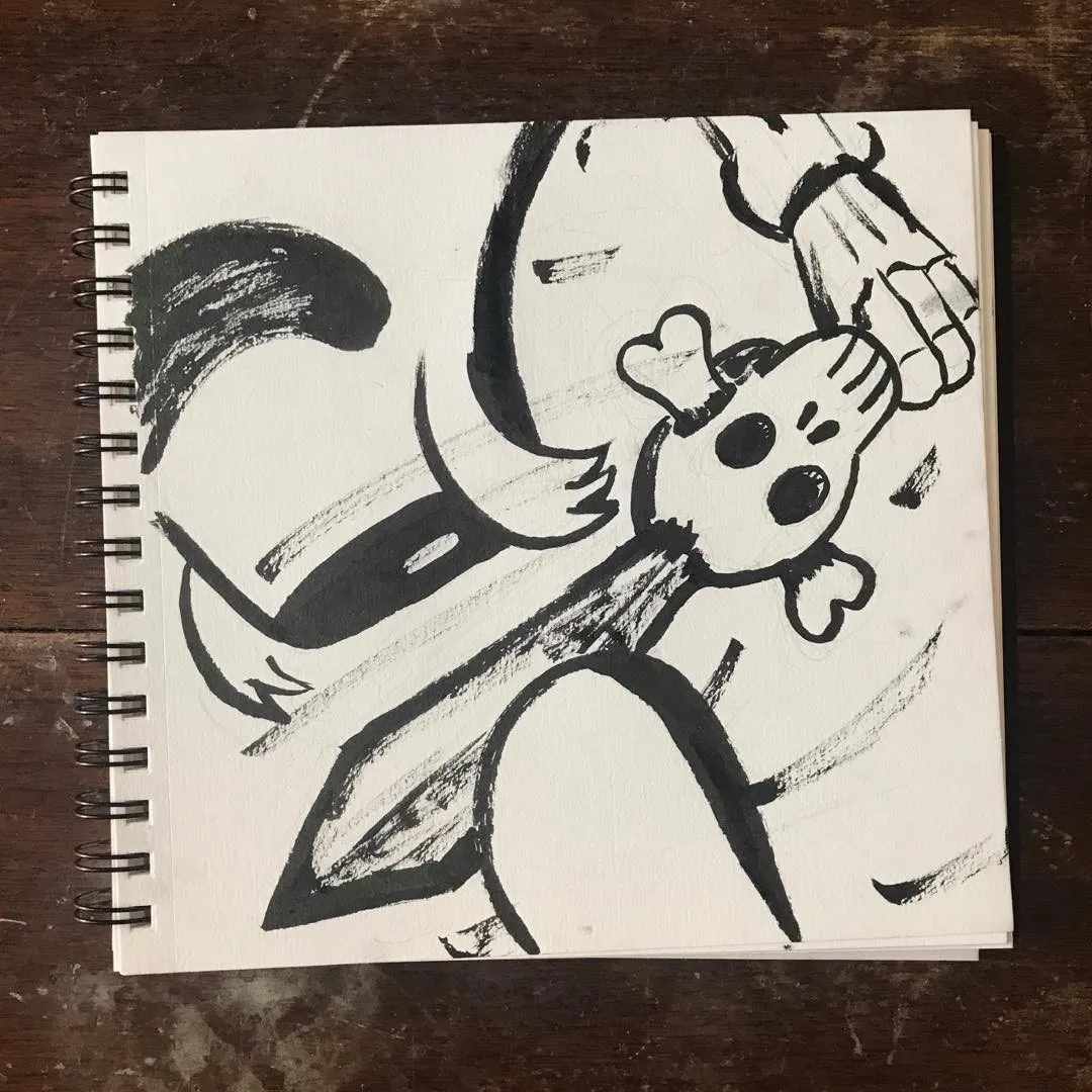 A stylized character drawing in black and gray pencil and ink, featuring a large tail and simple facial features, drawn on a page from a spiral sketchbook.