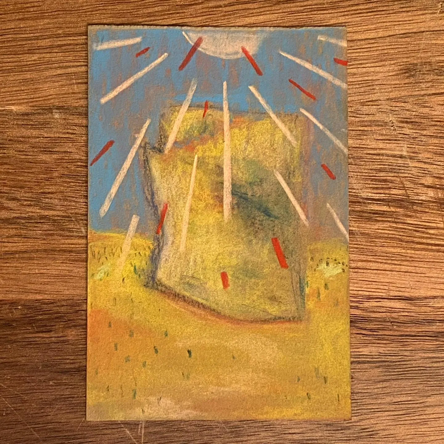 Abstract composition featuring a yellow mound under a blue sky, intersected by radiating white and red diagonal lines, resting on a textured gold base.