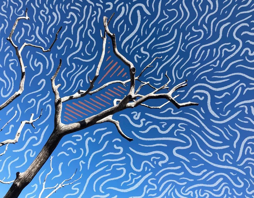 Bare, dark branches are silhouetted against a bright blue background patterned with dense, wavy white lines, framing a central orange geometric shape.