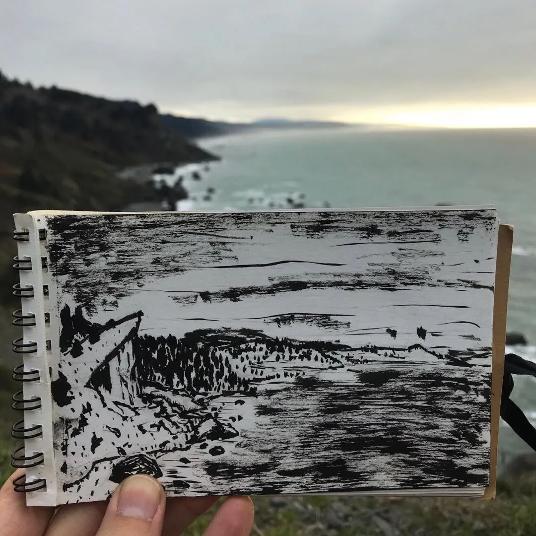 A black and white sketch of a coastal landscape featuring jagged rocks on the left, a row of trees in the middle ground, and a misty ocean meeting a cloudy sky.
