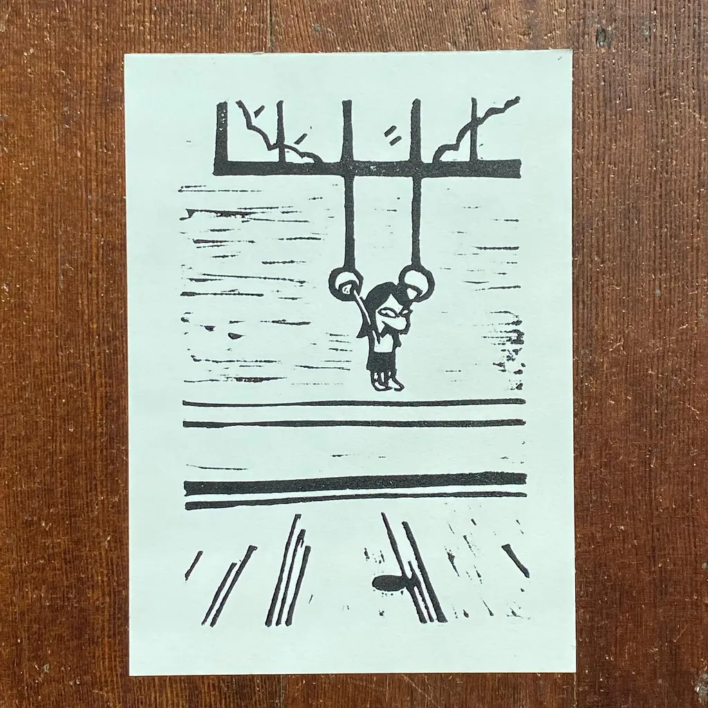 Black ink drawing on white paper depicts a stick figure hanging from a swing suspended by four vertical lines, positioned above two horizontal lines.