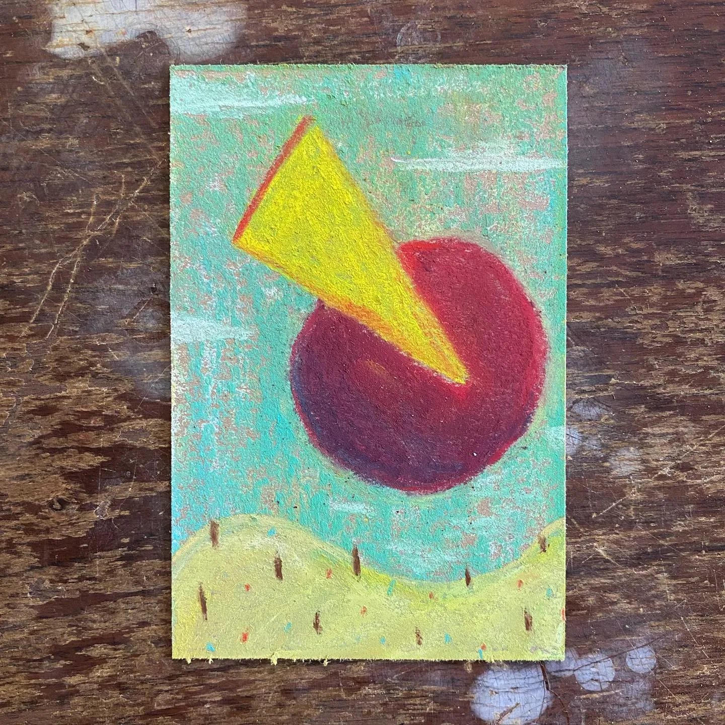 A composition featuring a large red circle and a bright yellow triangle crossing it, set against a turquoise background and resting above a yellow-green ground strip.