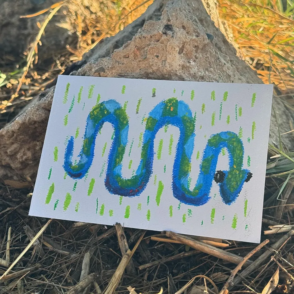 On white paper, a stylized, wavy blue creature is drawn, filled with varying shades of blue, set against a background of vertical dashed green marks.