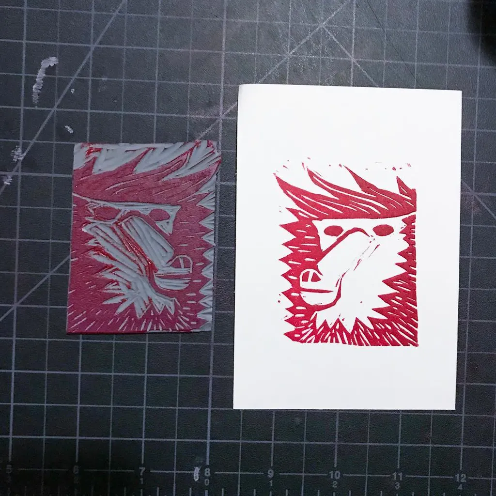 On a dark gray mat, two stylized red profiles are displayed: a small, jagged maroon design on the left, and a larger, bright red jagged design centered on a white card to the right.