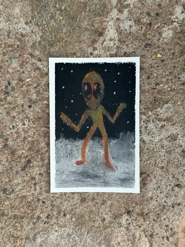 A simple, brown, humanoid alien figure with large yellow eyes stands in a black, starry void, positioned above a light gray ground on white paper.