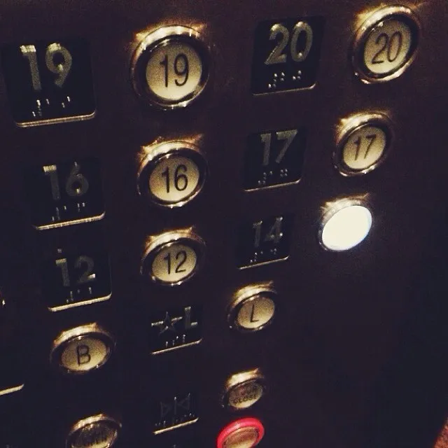 A dark, close-up view of a keypad featuring numbered buttons and function keys, with metallic gold lettering and illuminated white and red indicator lights.
