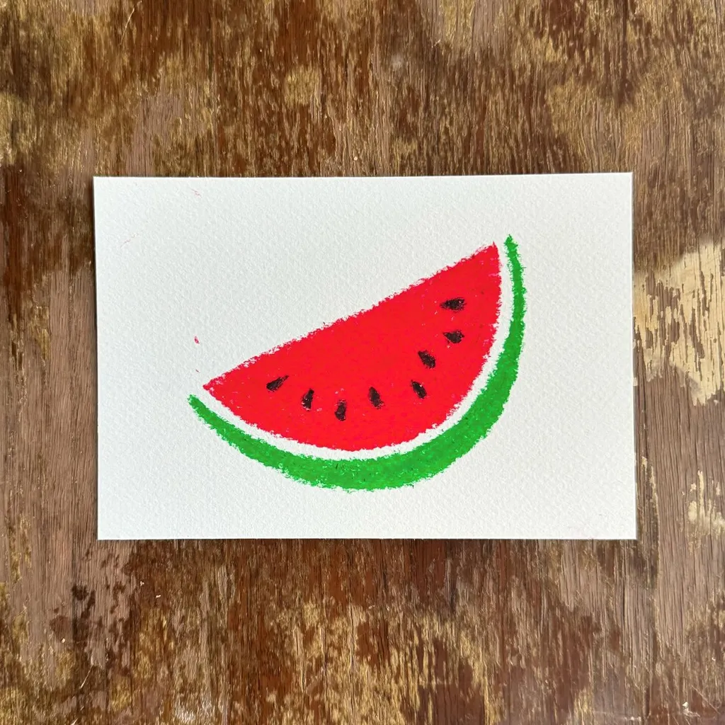 A drawing of a red and green watermelon slice with black seeds, rendered in visible strokes, centered on white paper placed on a dark, textured wooden background.