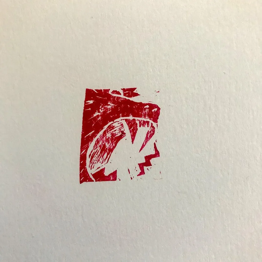 A distressed red rectangular mark is centered on white, containing a stylized, angular zigzag shape.