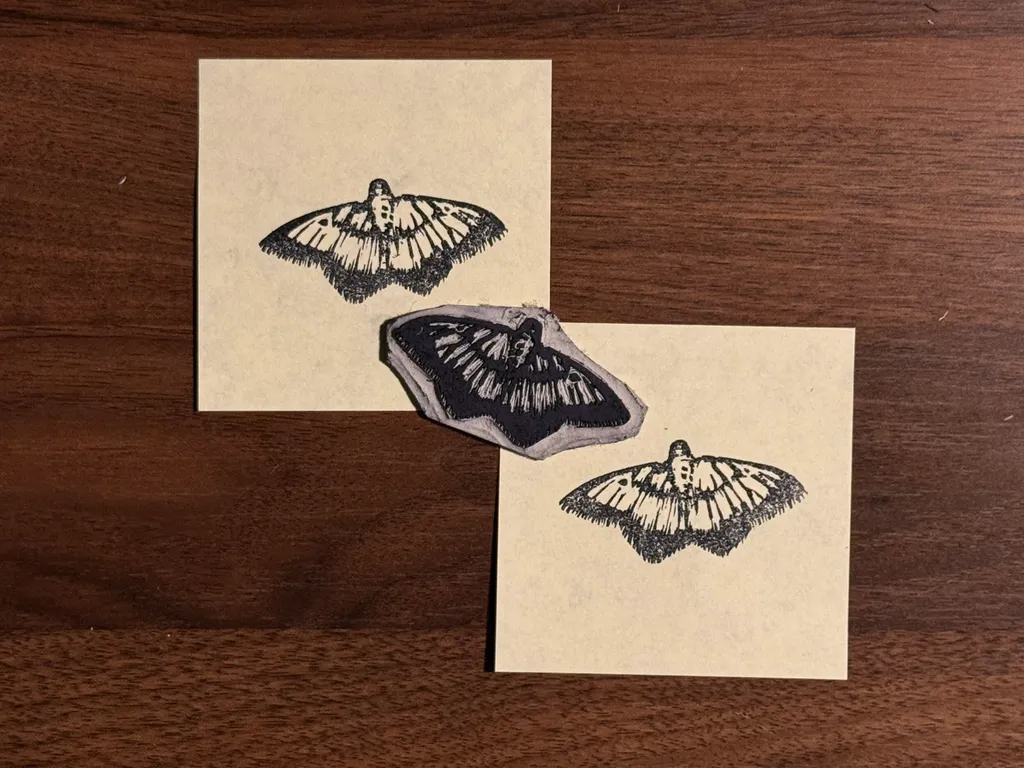 Three black drawings of bats are displayed on cream-colored paper sheets resting on a dark brown wooden background.