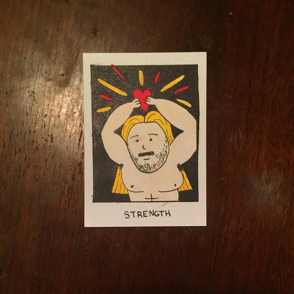 A stylized drawing on a card depicts a man with blonde hair holding a red heart surrounded by yellow rays, with the word STRENGTH printed beneath the figure.