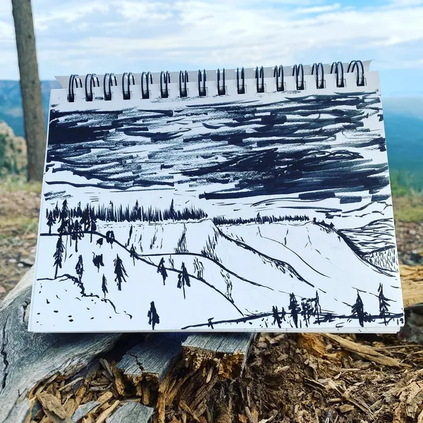 An open sketchbook displays a black and white landscape drawing featuring small figures and trees in the foreground, set against horizontal bands of dense scribbled lines.