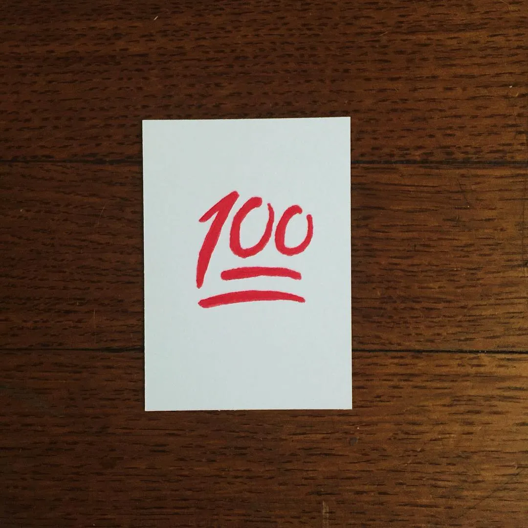 A white rectangle centered on dark wood shows red markings: the numerals 100, and beneath them, three parallel, curved red lines.