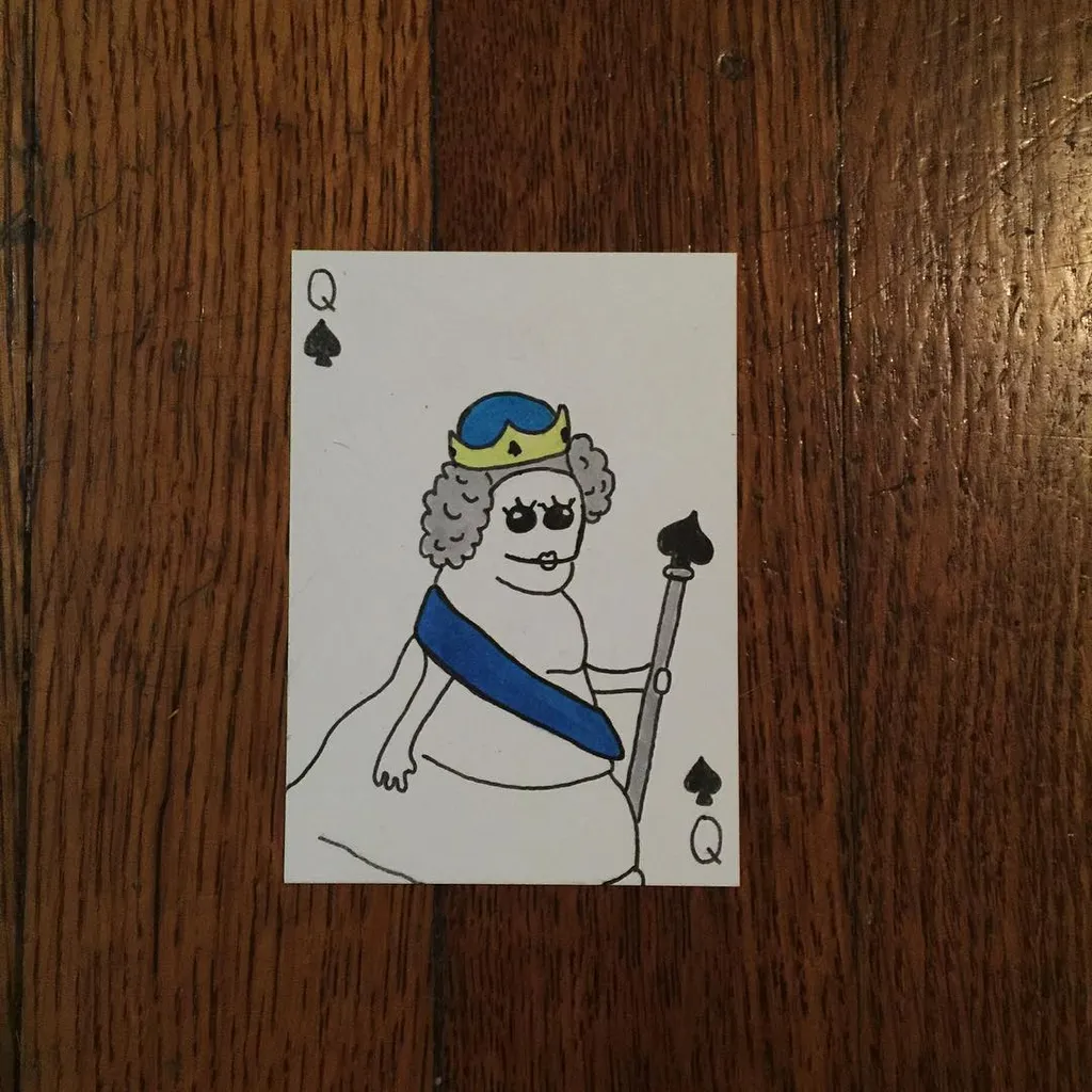 A stylized drawing of a queen with blue crown and sash, holding a staff, printed on a white card and set against a dark brown wooden surface.