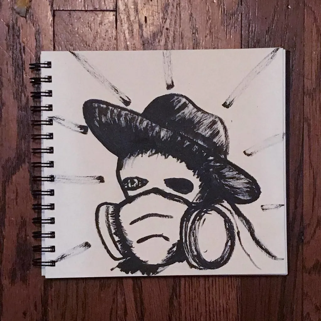 A black ink drawing on a spiral-bound sketchbook page depicts a stylized figure wearing a hat and gas mask, surrounded by radiating lines.