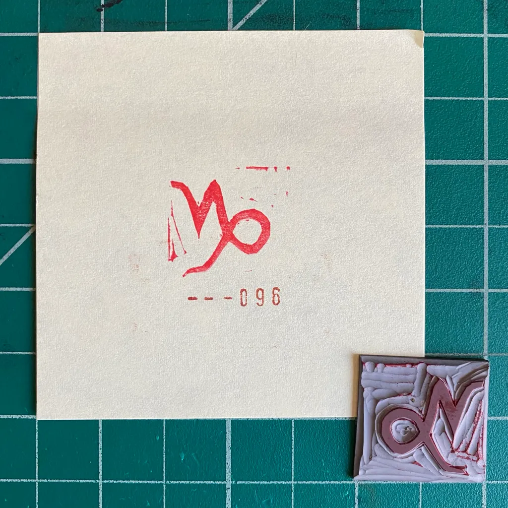 On a dark green grid background, a cream paper features a red stylized symbol and the numbers 960, next to a small square artwork with red and white layered textures.