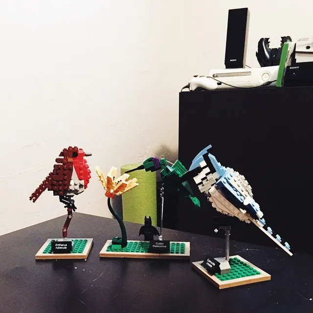 A collection of four geometric, assembled figures—a red dinosaur, a yellow plant, a black creature, and a blue mechanical beast—are displayed on green bases.