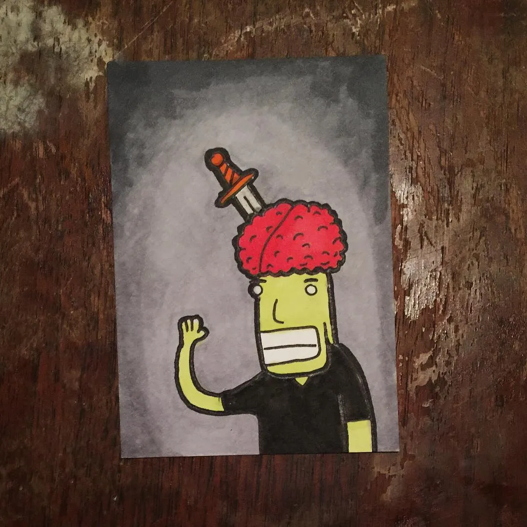 A stylized cartoon figure with pale green skin, a bright red textured head, and a small orange object, raises a fist against a solid gray background on a wooden surface.