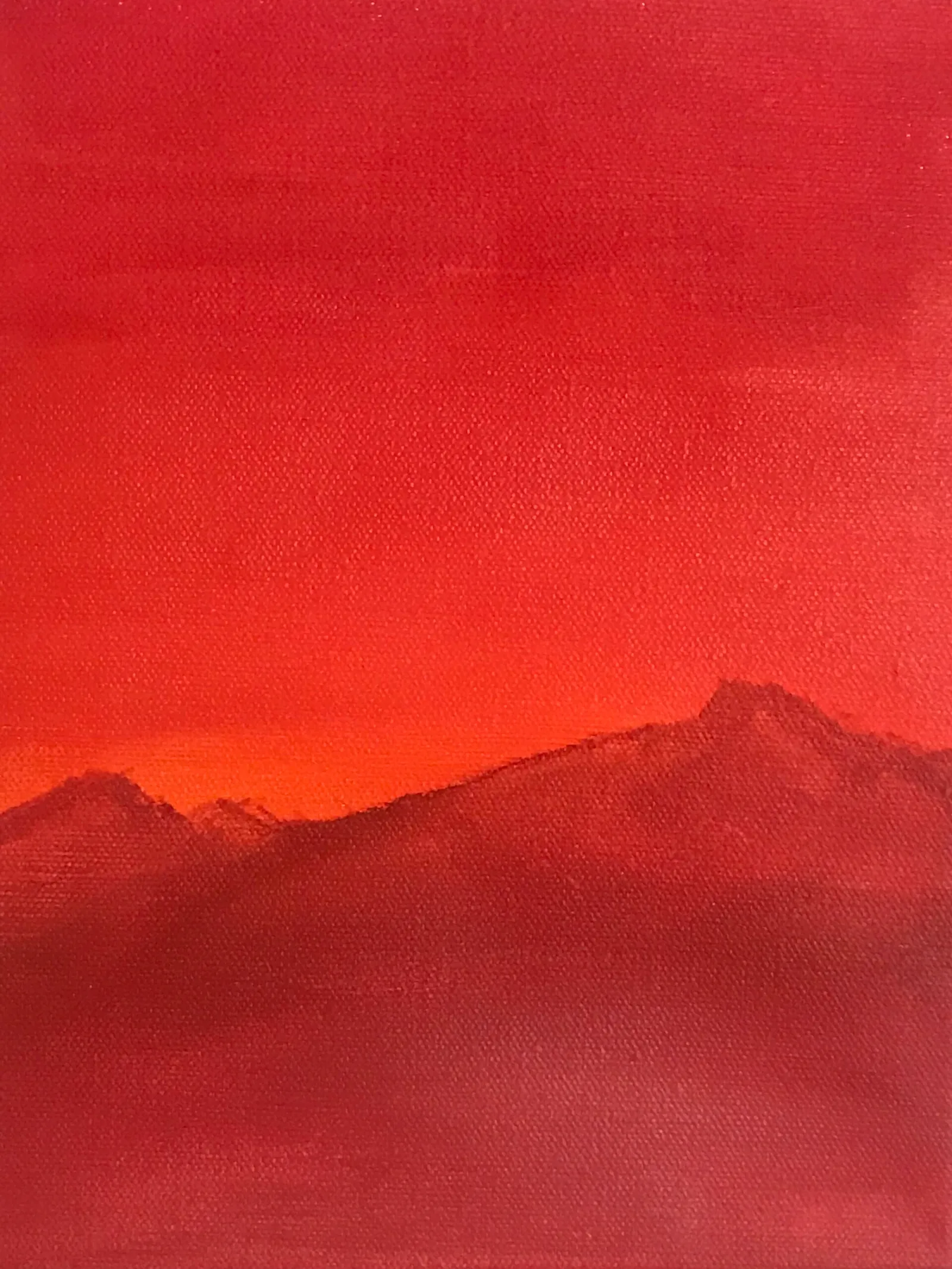 Silhouetted mountain layers in deep reds and oranges occupy the bottom third, set against a vast, textured field of saturated red and orange.