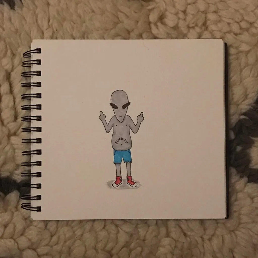 A drawing on a spiral notebook page features a pale, stick-figure character with a gray head, blue shorts, and red shoes, standing with raised hands and the text FUCK IT written on its chest.