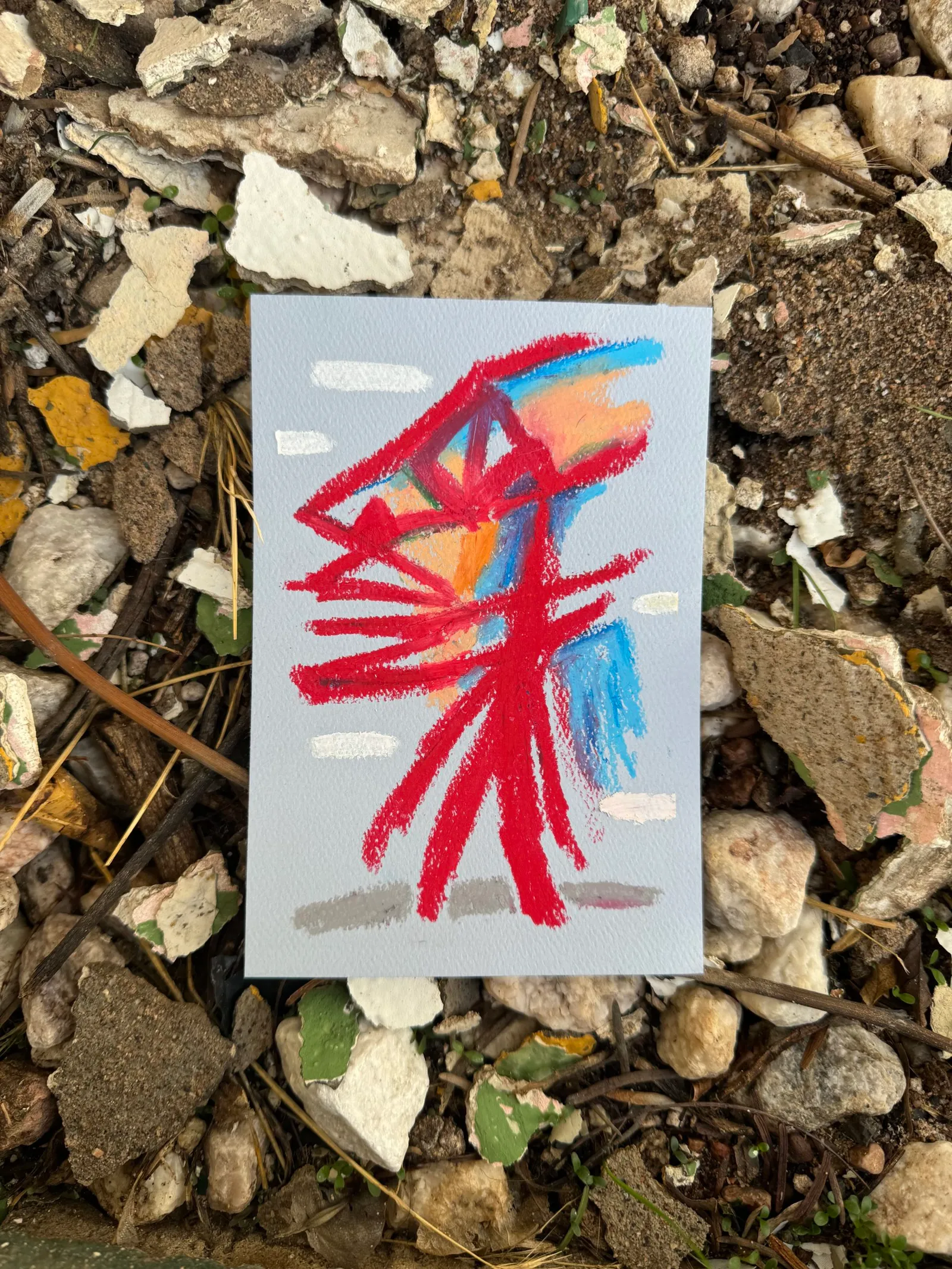A colorful abstract drawing on a light gray card features bold, overlapping strokes in red, blue, and orange, forming angular shapes.