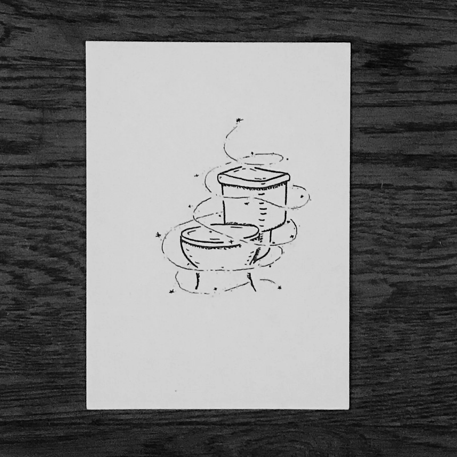 Black line drawing of stacked, simple round vessels—a bowl, a cylinder, and a smaller bowl—with surrounding sketchy lines and asterisks.