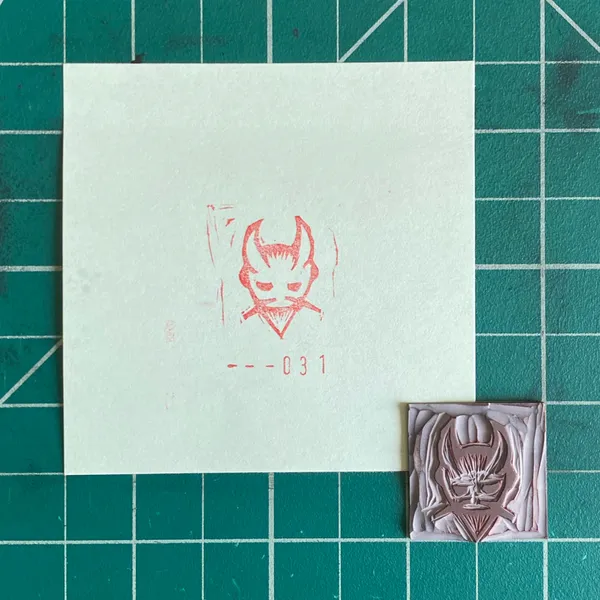 A composition on a teal grid features an off-white paper with a red drawing of a horned creature and the text --031, alongside a small, pale pink square relief featuring a stylized red mask.