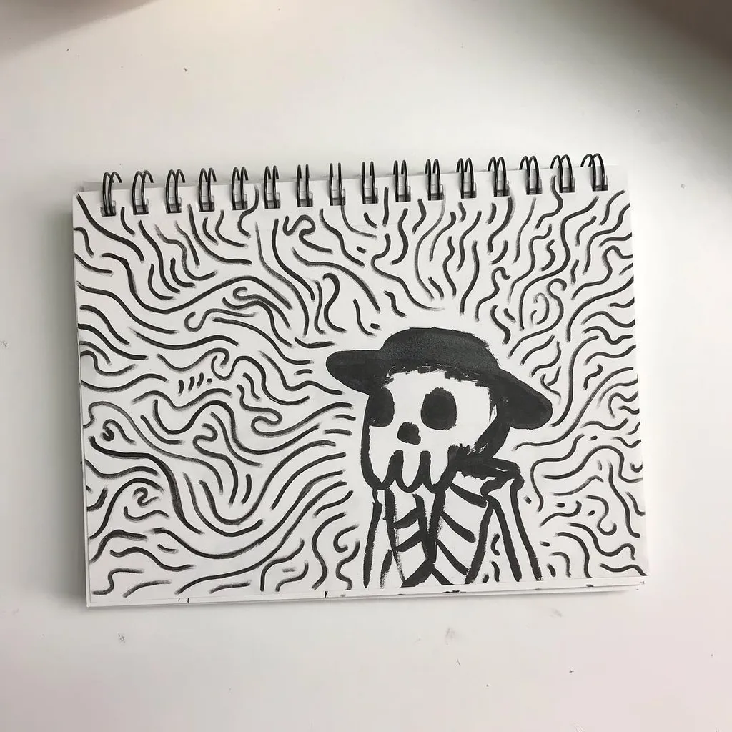 A black and white drawing on a spiral notepad features a skeleton wearing a hat, surrounded by intricate, wavy black lines that fill the page.