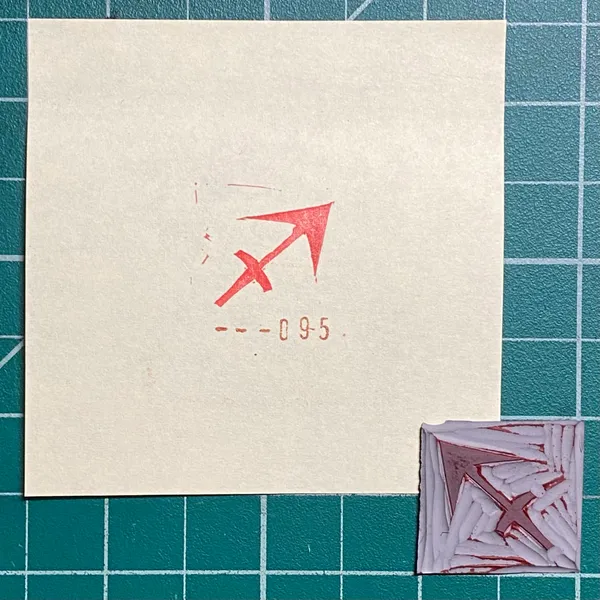 A cream paper displays a red arrow graphic and the numbers --09-5, positioned above a small, textured square featuring abstract reddish-brown and white patterns, all set on a teal grid.