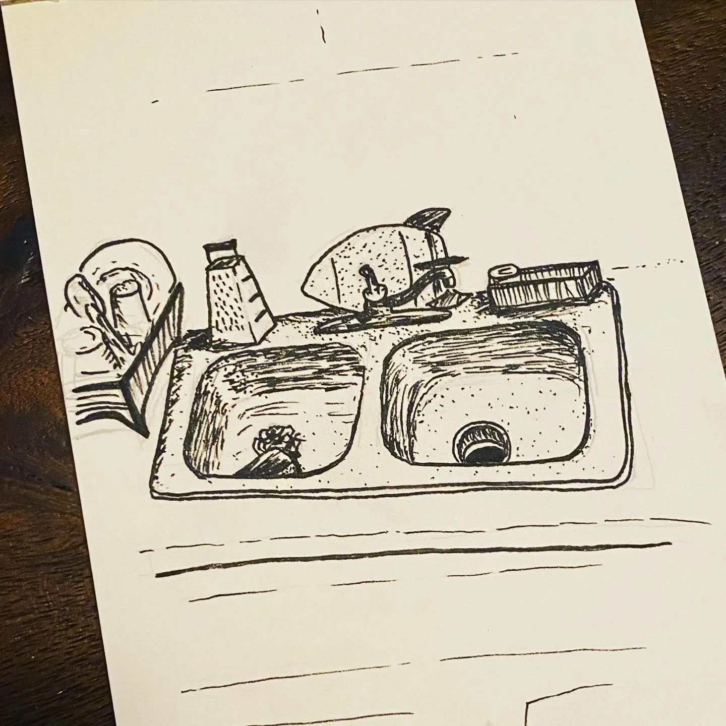 A line drawing on white paper depicting a double sink vanity unit, accompanied by sketched bathroom accessories such as soap dispensers and a toothbrush holder, overlaid with faint horizontal guidelines.