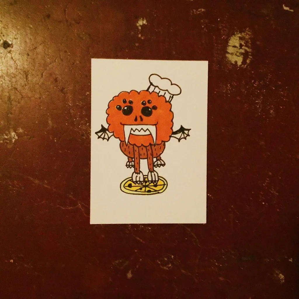 A cartoon orange pumpkin creature wearing a chef's hat and small black wings stands on a yellow plate, drawn on white paper set against a dark reddish-brown textured background.