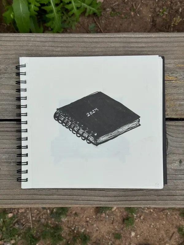 A stylized drawing of a closed, black journal with the year 2024 visible on the cover, placed on a sheet of white paper atop a wooden surface.