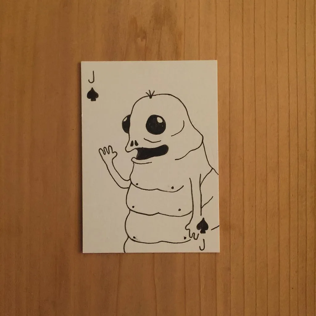 A black and white line drawing on a playing card depicts a cartoon ghost with large eyes and a smile, holding a spade symbol in its hand.