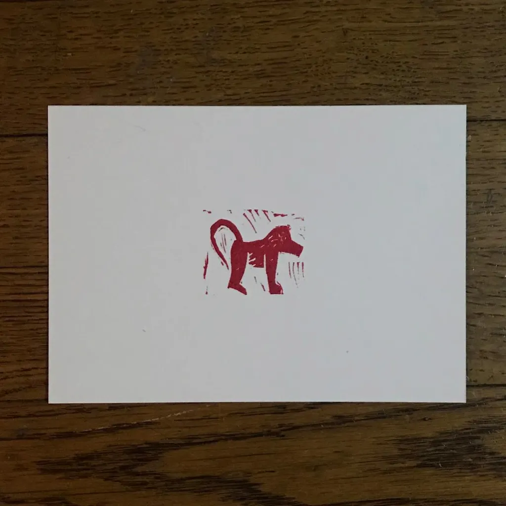 A stylized, crouching animal drawn in deep red ink is centered on a white card, accompanied by rough red scribbles that frame the figure.