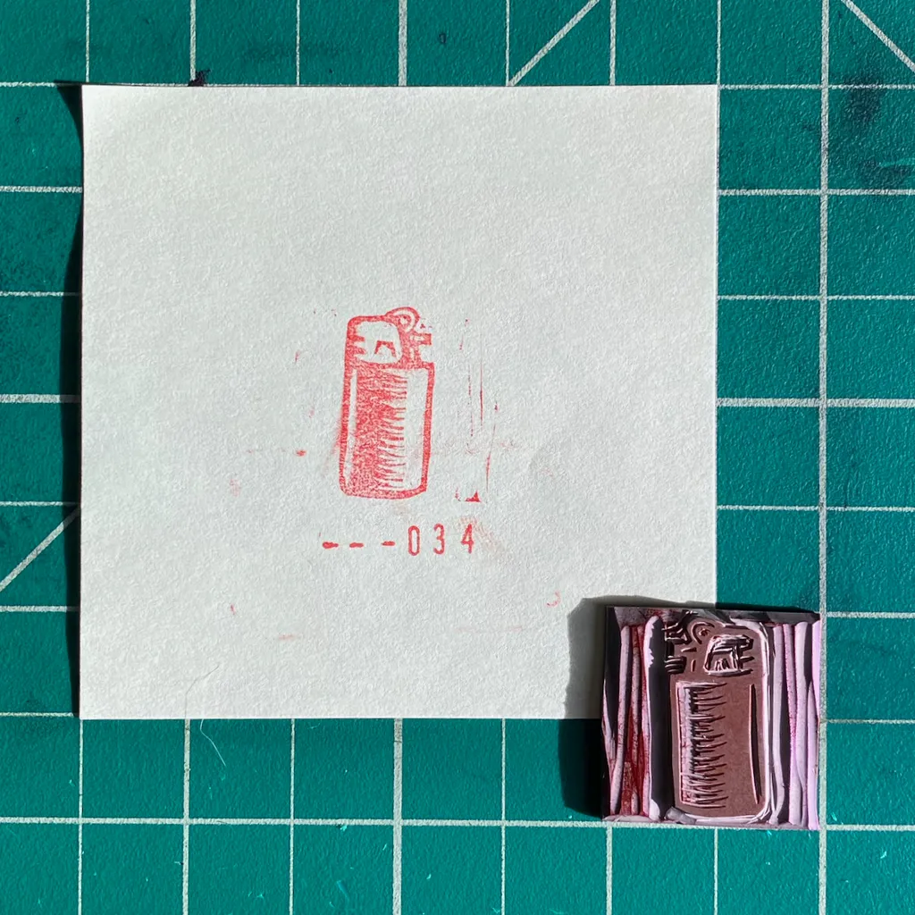 A white card on a teal grid displays a red outline drawing of a spray can and the numbers --034, positioned above a small stack of colored rectangles in shades of red and purple.