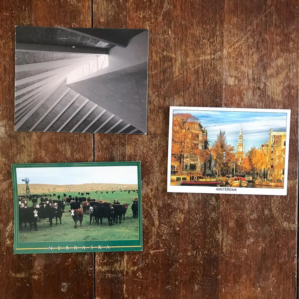 Five photographs are displayed on dark wood, featuring abstract black and white architectural shots, a color photo of grazing cattle, and two colorful street scenes of canals and buildings.