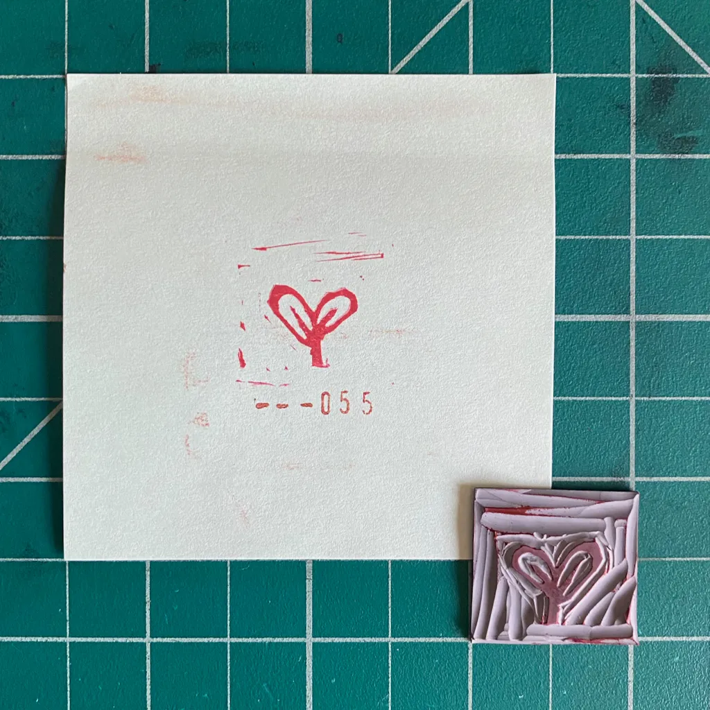 On a teal grid, a large cream square displays a red heart and the numbers --055, positioned above a smaller, textured pink square featuring an embossed heart design.