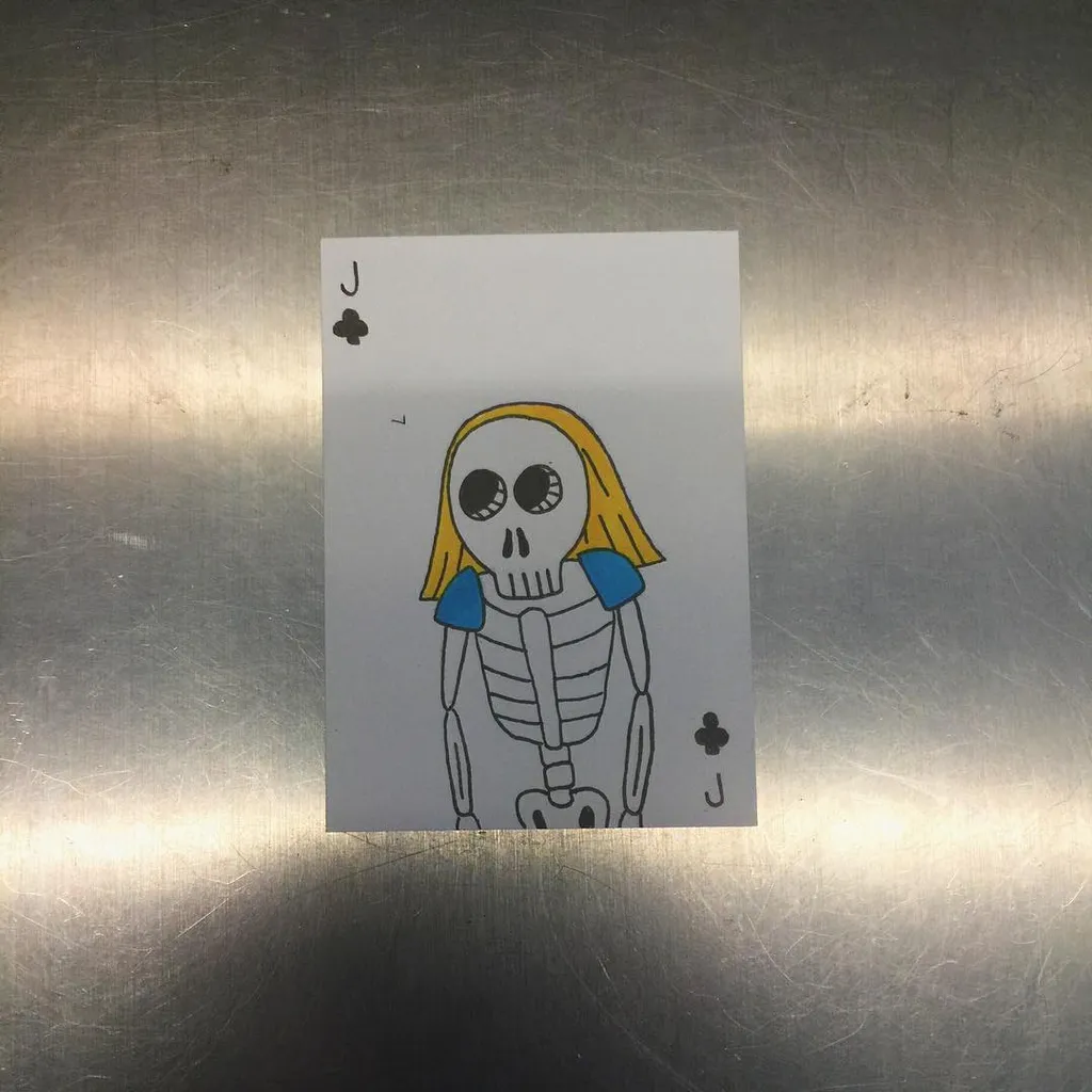 Two playing cards, both Jacks of Clubs, are displayed on a reflective, brushed metal surface; the cards feature a yellow-haired skeleton character wearing blue shoulder pads.