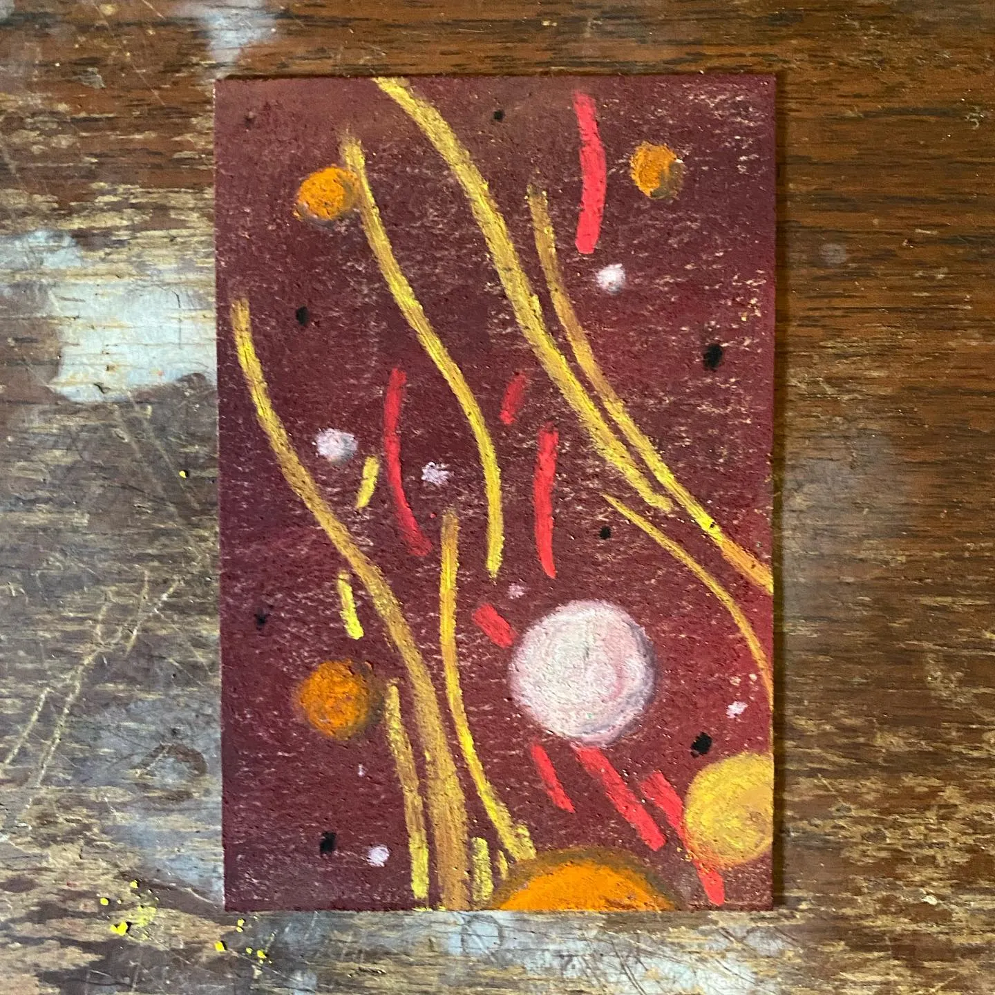 The artwork features a dark reddish-brown background with flowing gold lines, vertical red streaks, and various scattered circular shapes in orange, yellow, and pale pink.