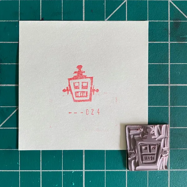 On a teal grid, a white paper features a red drawing of a stylized gate and the number --024, next to a small, light purple square with an embossed gate design.
