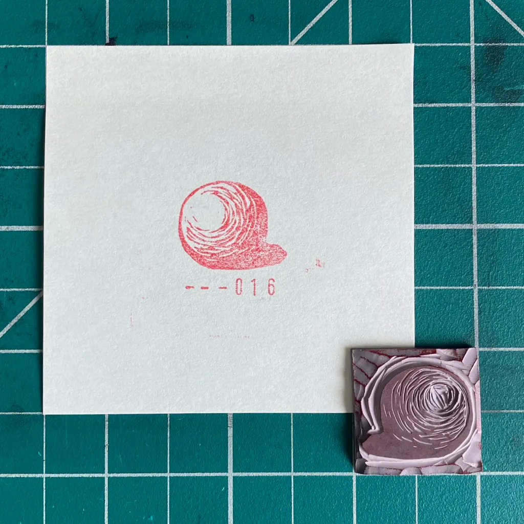 A white card on a teal grid displays a reddish-pink sketch of a head with a spiral and the number --016, positioned above a small, textured square featuring a concentric purple spiral.
