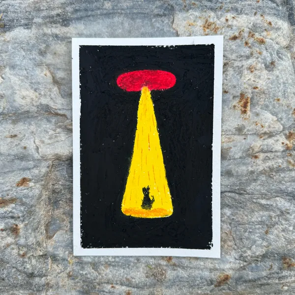 A black square panel features a yellow, inverted triangle topped by a red rectangle, with a small dark figure positioned at the base, resting on a rough gray stone surface.