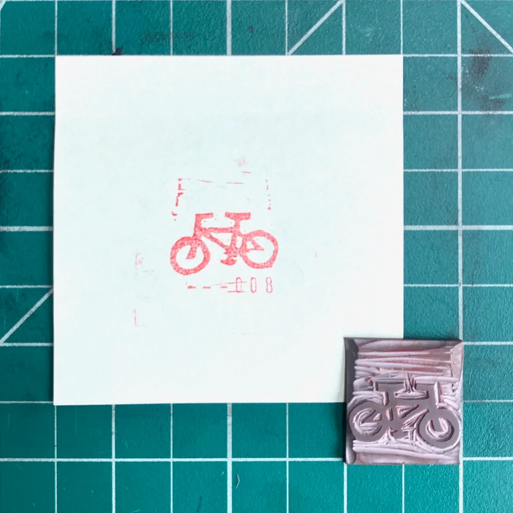 A white square on a teal grid displays a red line drawing of a bicycle and the numbers 008, next to a small, textured purple rectangle featuring a layered bicycle design.
