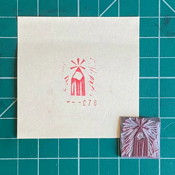 A cream square paper on a teal grid displays a red stylized starburst and the number --076, next to a small, textured pink and white square featuring a similar design.