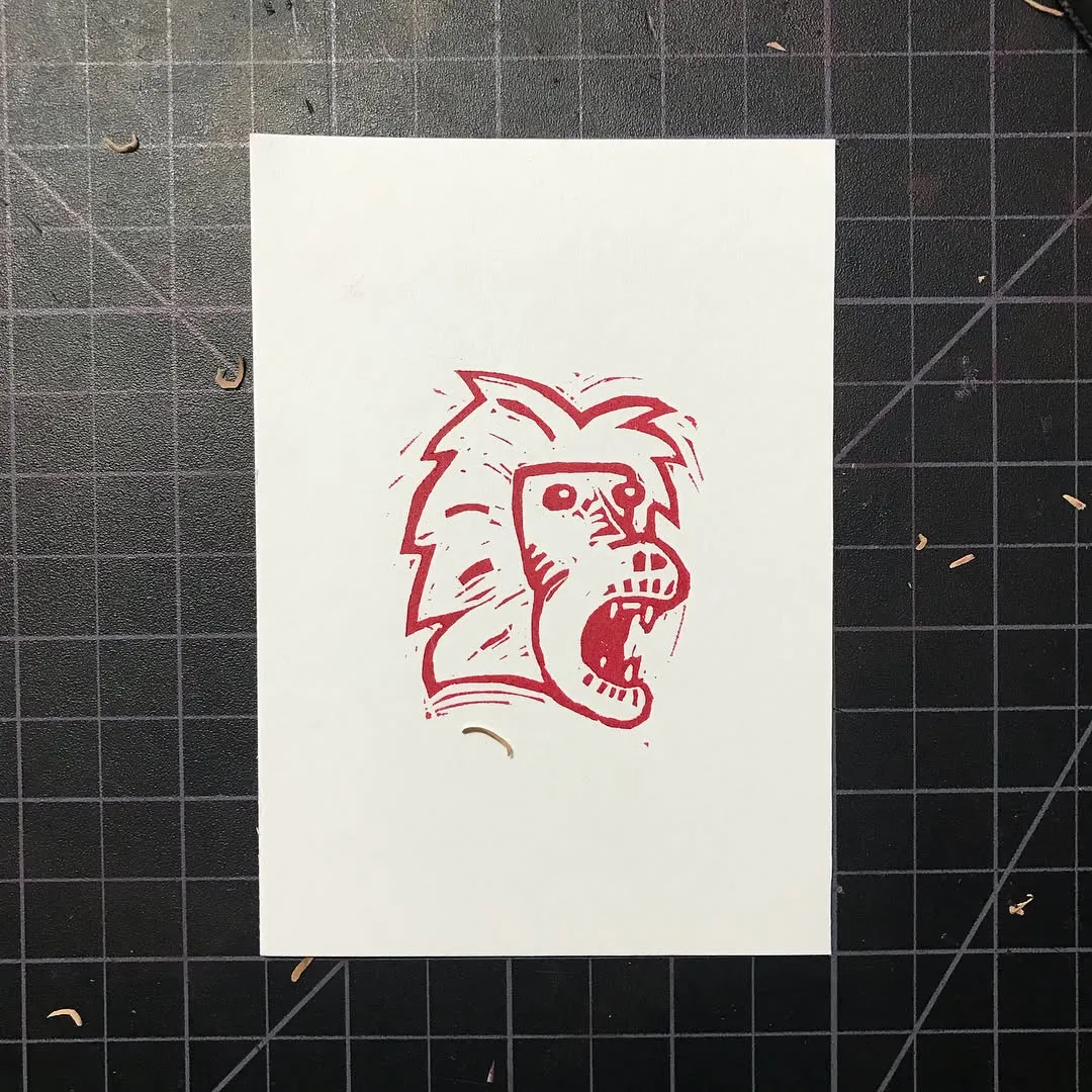 A stylized red drawing of a snarling dog's head is centered on white paper, which is set against a dark, gridded background.